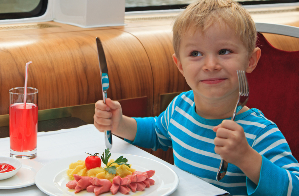 Kid eating food at a table with silverware